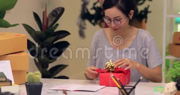 女人用纸包裹圣诞节或其他节日手工礼物视频的预览图