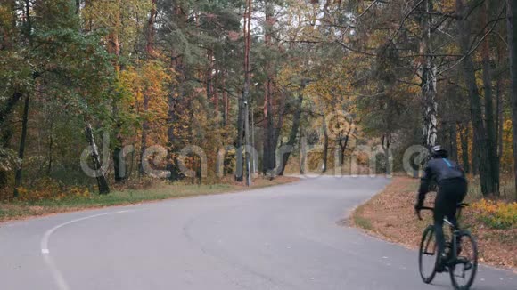 专业骑自行车的黑色头盔和自行车服装是密集的培训道路自行车在秋季城市公园男青年运动员视频的预览图