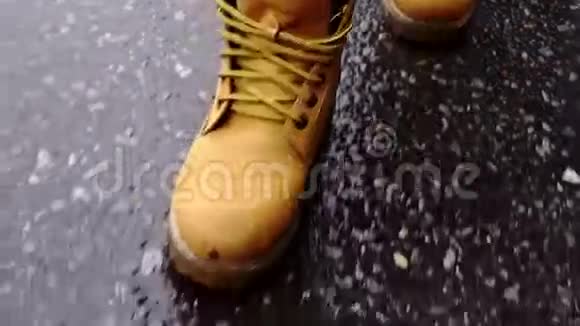 穿靴子的女人在潮湿的沥青中行走视频的预览图
