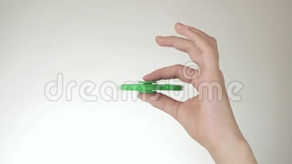 一个十几岁的女孩的手在白色背景的股票视频上旋转一个绿色的烦躁旋转者视频的预览图