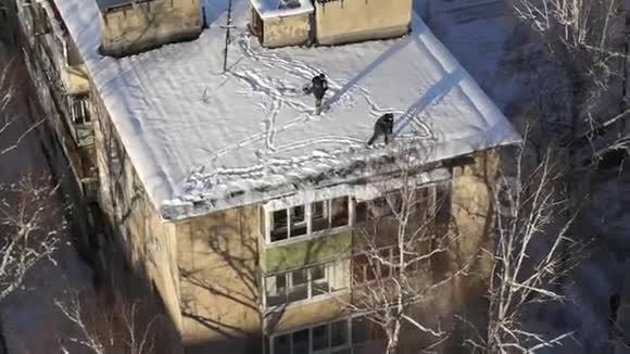 人们在降雪时用铁锹把屋顶上的雪清除掉视频的预览图