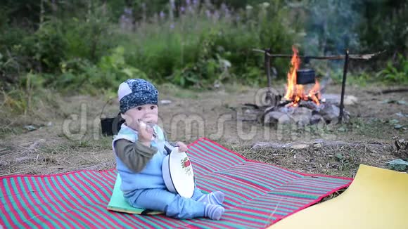 小游客坐在篝火旁玩盘子和勺子视频的预览图