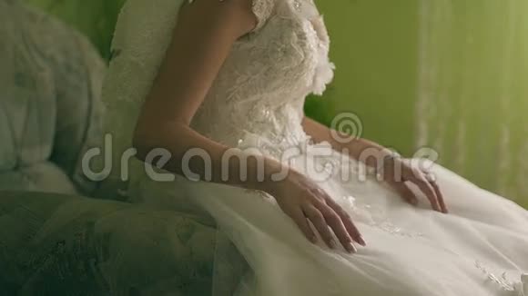 这位穿着白色连衣裙的美丽有趣的新娘坐在棕色的背景上视频的预览图