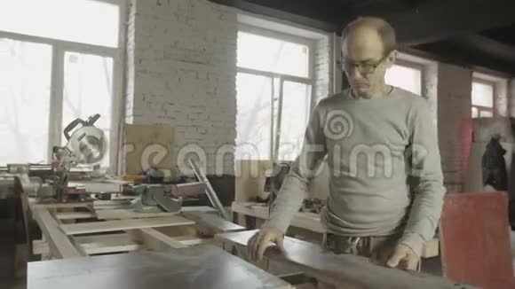专业的成年木匠从工作台面上卸下抛光木板视频的预览图