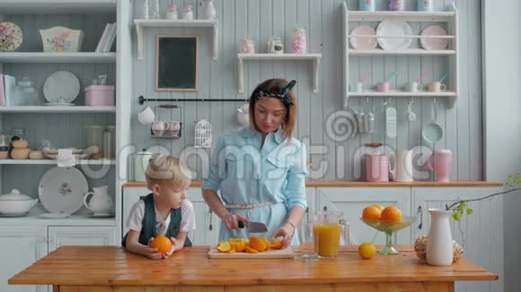健康的人小男孩和小妈妈早上在厨房里做新鲜橙汁视频的预览图
