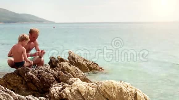 父亲教儿子如何在多岩石的亚得里亚海海岸钓鱼视频的预览图