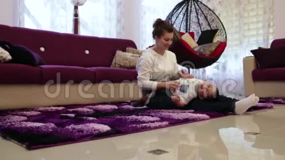 年轻的母亲和躺在地上的小儿子玩耍视频的预览图