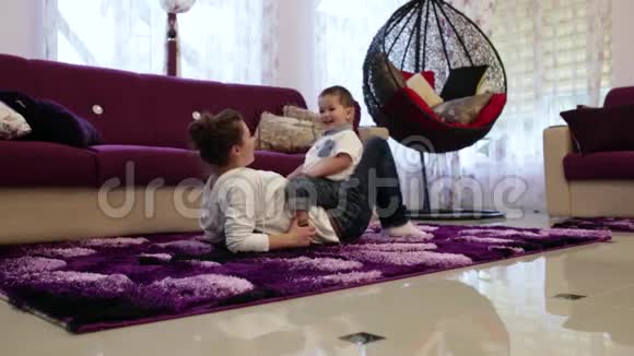 年轻的母亲和躺在地上的小儿子玩耍视频的预览图
