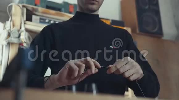 穿着黑色高领毛衣的高个子男人用电线和电线工作视频的预览图
