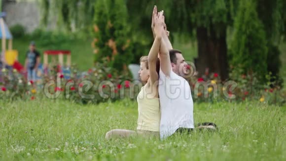 一个男人和一个女人在做运动之前伸展身体年轻的瑜伽教练在绿草如茵的城市公园练习视频的预览图