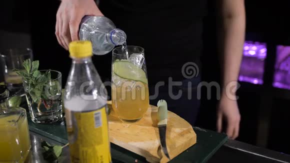 酒保正在做鸡尾酒把苏打水倒入装有冰块的杯子里视频的预览图