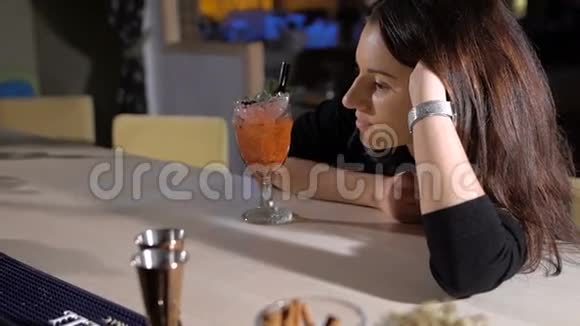 漂亮的黑发女人在酒吧后面喝酒精鸡尾酒视频的预览图