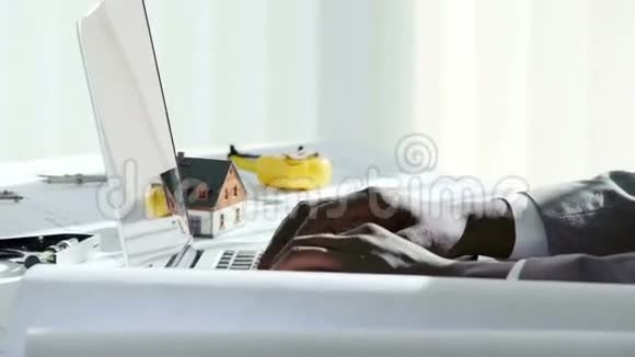 在阳光明媚的日子里在白色的现代办公室里年轻的黑人商人用手在笔记本电脑键盘上打字视频的预览图