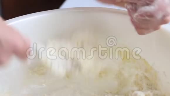 奶酪蛋糕的准备一个女人卷成面团容器里放着干酪一个鸡蛋被打掉了视频的预览图