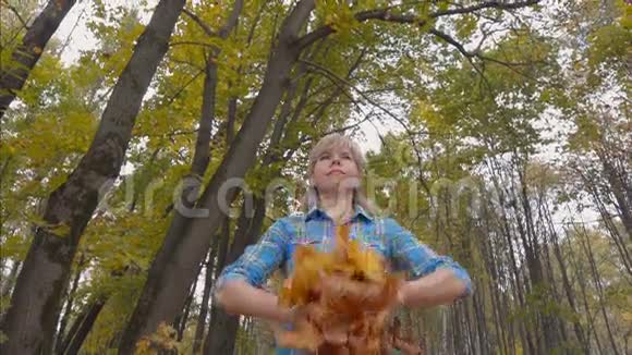 秋天公园的年轻女子举起一臂枫叶视频的预览图