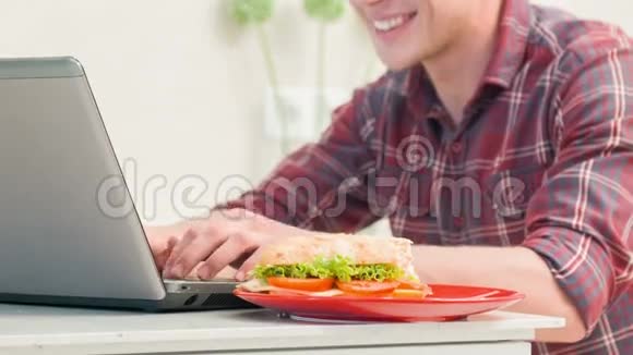 特写男在电脑前吃三明治视频的预览图