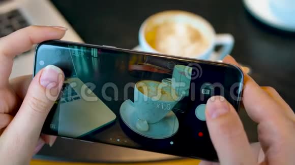 女孩在一家咖啡馆里用智能手机拍咖啡视频的预览图
