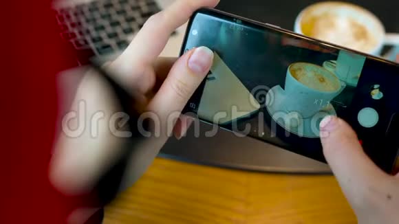 女孩在一家咖啡馆里用智能手机拍咖啡视频的预览图