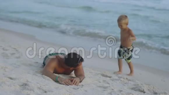 年轻的父亲和他的小儿子在海滩玩得很开心视频的预览图