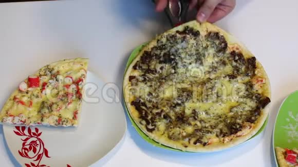 一个人用剪刀用蘑菇切比萨饼把切好的一块转移到另一个盘子里视频的预览图