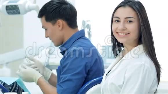 坐在牙医和牙齿旁边的女助手视频的预览图