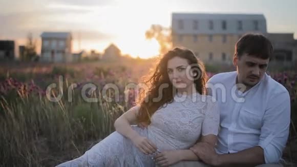 年轻的白种人夫妇坐在田野里视频的预览图
