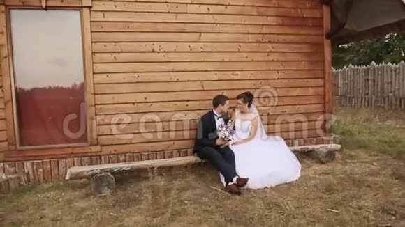 新郎新娘坐在老房子的长凳上视频的预览图