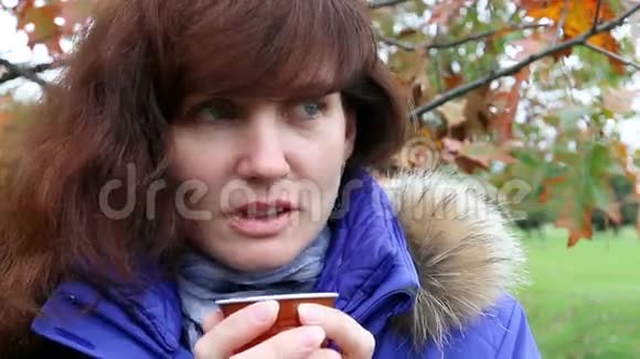 女人在秋天公园喝咖啡户外活动视频的预览图