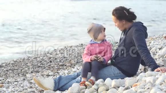 母亲和孩子坐在海滩上享受日落视频的预览图