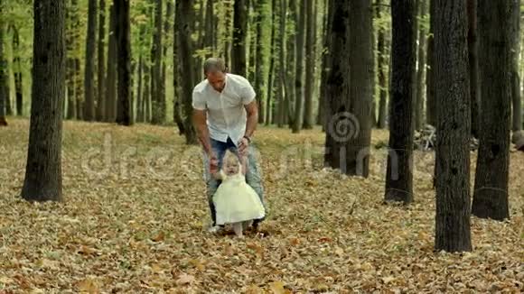 父亲和他的孩子迈出了秋天公园的第一步视频的预览图