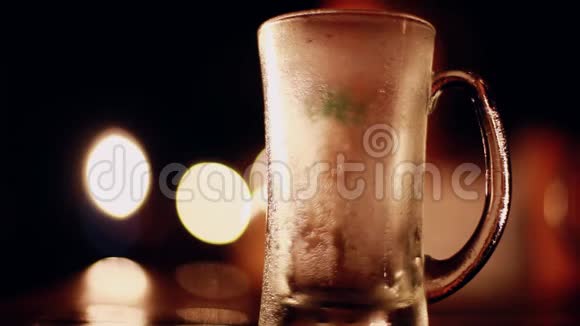 啤酒从瓶子里倒入玻璃在酒吧或酒吧的桌子上放一杯啤酒放在美丽的bokeh灯上就像视频的预览图