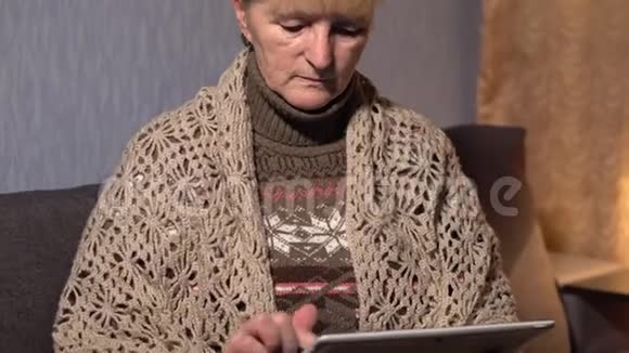 一位老年妇女在家中享用平板电脑视频的预览图