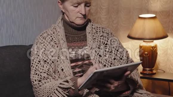 一位老年妇女在家中享用平板电脑视频的预览图