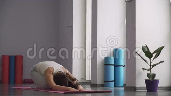 女人坐在垫子上做放松的练习健身馆视频的预览图