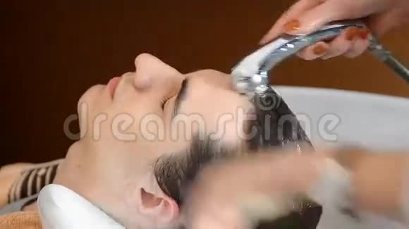 男理发师在理发店里洗头用钢笔写字视频的预览图