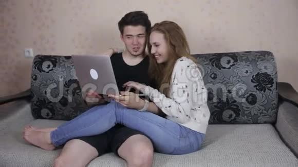 家庭技术和关系概念英俊的夫妇与笔记本电脑在家视频的预览图