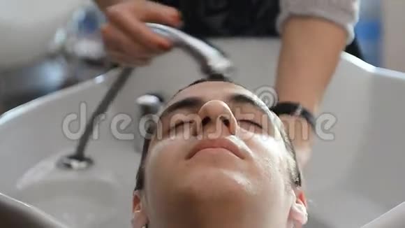 男理发师在理发店里洗头用钢笔写字视频的预览图