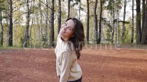 一个年轻的女人走在秋天的公园里黑发女人在森林里跳跃和跳舞自由概念视频的预览图