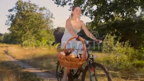 日落时分美丽的年轻女子骑着自行车穿过田野视频的预览图