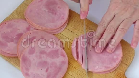 女人的手拿刀切香肠在木切割板上特写视频的预览图