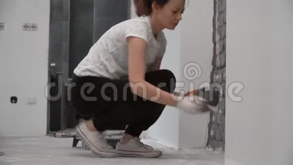 用刷子把年轻女子的砖墙涂成灰色视频的预览图