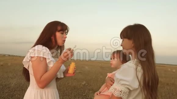 日落时分女儿和母亲正在公园里吹泡泡慢动作快乐的妈妈在玩孩子吹箫视频的预览图