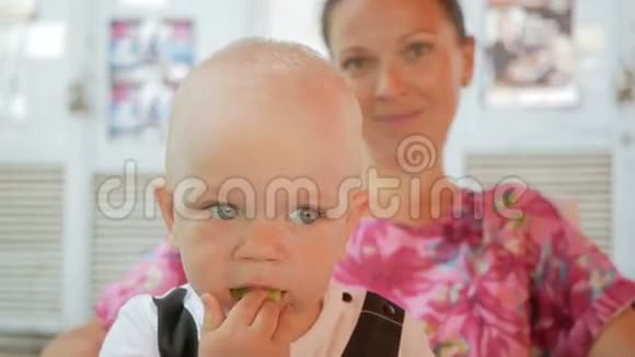 妈妈和宝宝穿着一件漂亮的裙子和蝴蝶在街上的咖啡馆里吃饭小孩吃黄瓜沙拉视频的预览图