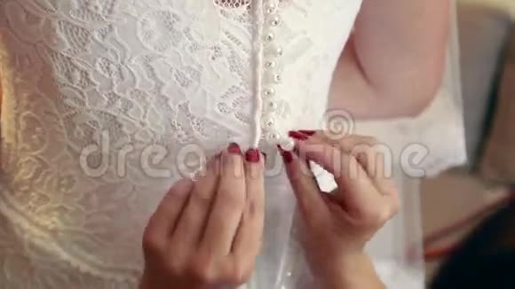 为婚礼做准备母亲或伴娘帮助年轻新娘穿新娘礼服年轻人的早晨视频的预览图