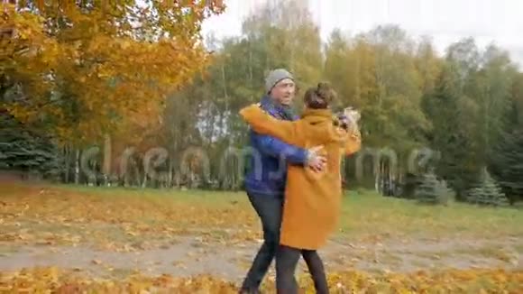 父亲教女儿在秋天公园跳舞然而他们笑了笑许多美丽的黄叶视频的预览图
