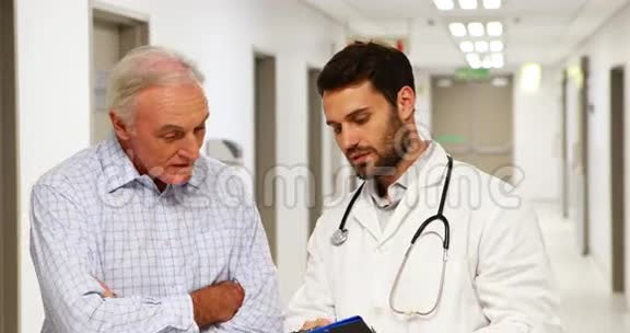 医生和病人在走廊上讨论剪贴板视频的预览图