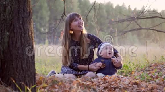 妈妈和她的小男孩在秋天的森林里落叶视频的预览图