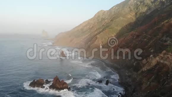 大西洋波浪在山的背景和日落在特内里费岛金丝雀群岛和美丽的自然一堆石头视频的预览图