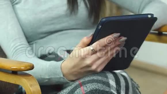 漂亮的女孩用平板电脑坐在家里舒适的椅子上视频的预览图
