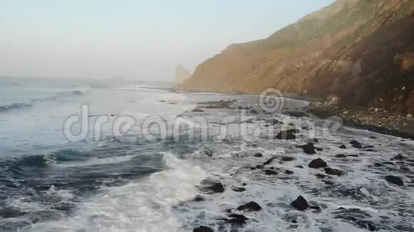 大西洋波浪在山的背景和日落在特内里费岛金丝雀群岛和美丽的自然一堆石头视频的预览图